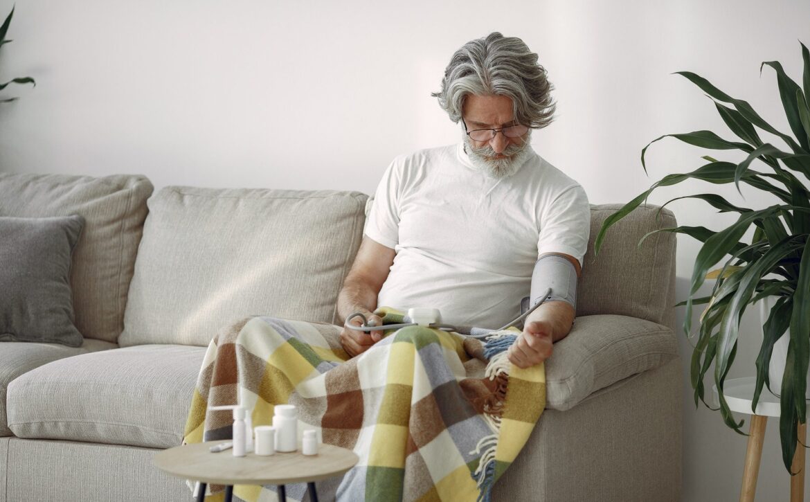 Mature man sitting and measuring his blood pressure